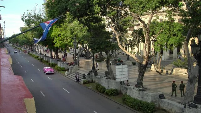high angle establishing shot of classic convertible car on street with cuban flag in Havana, Cuba