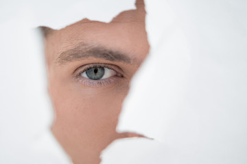 close up. businessman looking through a hole in the paper wall