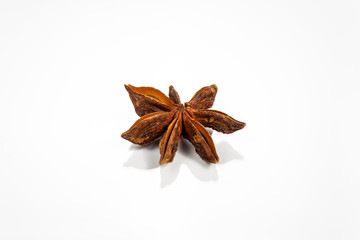 Single anise star isolated on white reflective surface
