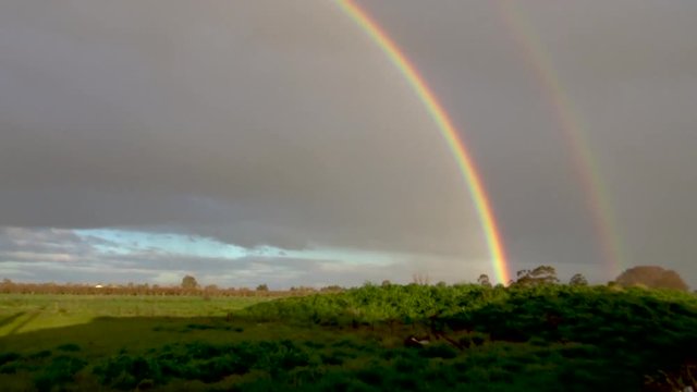 A full semi circle double rainbow shot from left to right with both ends touching ground.