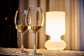 Glass white wine on the table with a burning lamp in a cozy restaurant.