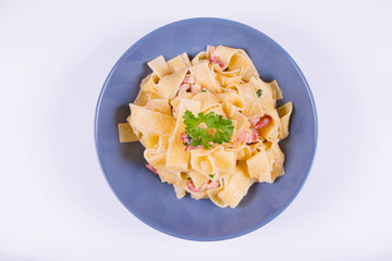 Pappardelle Carbonara with some parsley on a blue plate on a white background