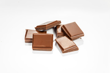 Pieces of chocolate isolated on white reflective background