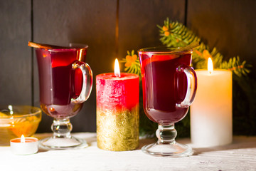 Mulled wine and burning candle on dark background. Christmas mulled wine, cinnamon sticks and honey. Alcohol drink of wine and honey. Festive drink and Christmas tree branches