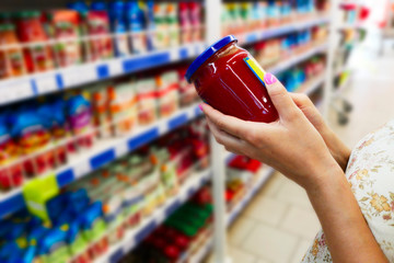 Glass jar of sauce in the hands of the buyer. Sauce in the hands of the buyer at the grocery store