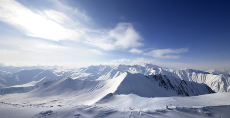 Fototapeta na wymiar Panoramic view on snowy sunlight mountains at winter evening