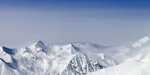 Panoramic view on snowy sunlight mountains in haze