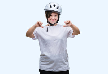 Young adult cyclist woman with down syndrome wearing safety helmet over isolated background looking confident with smile on face, pointing oneself with fingers proud and happy.