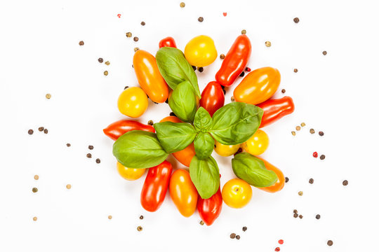 Centered composition of basil, pepper and cherry tomatoes, on white background