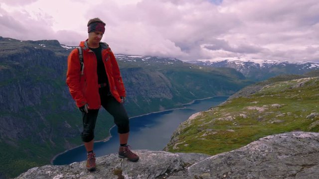 Male traveler standing and walks the top of the mountain in the Nordic fjord
