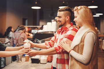 Young couple in cafe ordered coffee from barista in paper cups to take