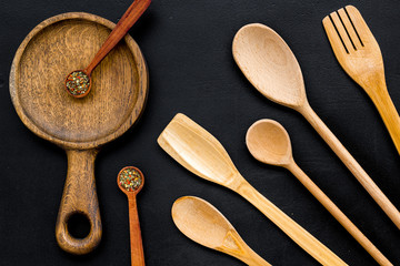 Woodenware set with pan, spoons and forks on black background top view