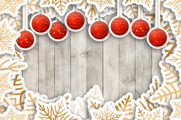 Brown wooden table with paper cut gold snowflakes and christmas balls.