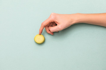 Female hands touching green macaroon cake. Top view, flat lay. Copyspace for text