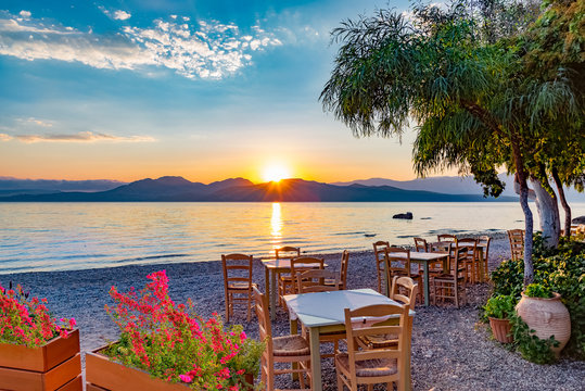 Romantic scene with table and chairs on a terrace outdoor at sunrise on Nikiana beach in Lefkada island