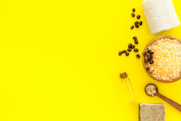 Aromatherapy and spa concept. Spa salt with coffee scent near soap and loofah on yellow background top view copy space