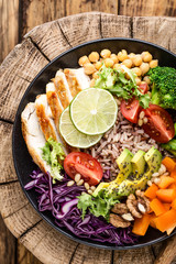 Buddha bowl salad with chicken fillet, brown rice, avocado, pepper, tomato, broccoli, red cabbage, chickpea, fresh lettuce salad, pine nuts and walnuts. healthy food. balanced diet eating. Top view