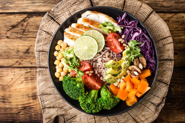 Buddha bowl salad with chicken fillet, brown rice, avocado, pepper, tomato, broccoli, red cabbage,...