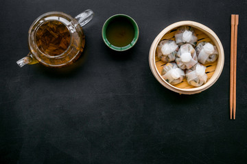 Chinese food set with dim sum, sticks and tea on black background top view copy space