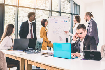 Business People Corporate Meeting Board Room Concept. Handsome businessman using phone and sitting at the table with colleagues speaking on background