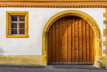 Fassade eines restaurierten Fachwerkhauses teils verputzt mit Fenster und Einfahrt mit Rundbogen und eingepasstem Holztor