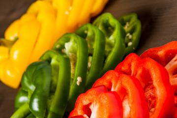 Fresh bell pepper slices isolated on wooden cutting board