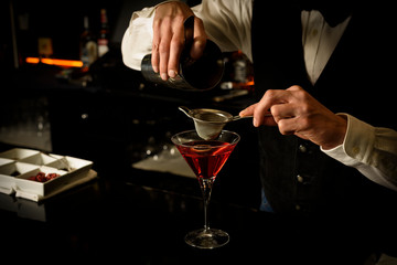 Young bartender preparing a delicious cocktail at the bar of a cocktail bar.