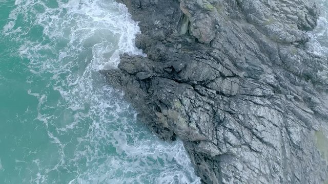 Aerial fly over of rough ocean tides breaking against the rugged rock cliffs in Durness, Scotland
