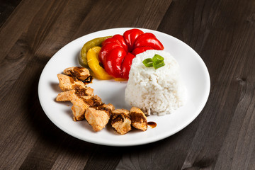 Chinese food on a white plate with rice, paprika and chicken 