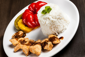 Chinese food on a white plate with rice, paprika and chicken 