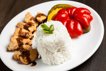 Chinese food on a white plate with rice, paprika and chicken 
