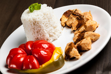 Chinese food on a white plate with rice, paprika and chicken 