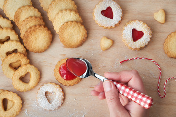 Top view of traditional Christmas Linzer cookies filled with strawberry jam on wooden board