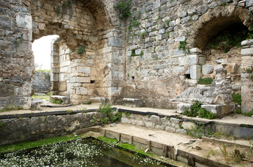 Ruins of ancient fausta bath pool and  relaxing man sculpture in Miletus ancient city, Turkey