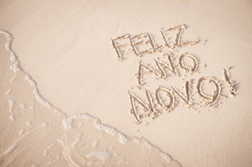 Feliz Ano Novo message (Happy New Year in Portuguese) handwritten on the smooth sand of Copacabana Beach in Rio de Janeiro, Brazil