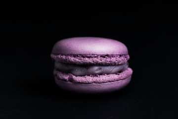Sweet purple macaroon on black background.