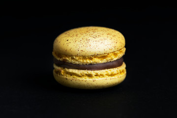 Sweet yellow macaroon isolated on black background.