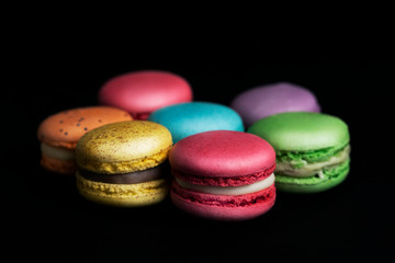 Sweet and colourful french macaroons on black background.