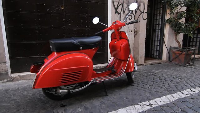 Red moped parked on cobblestone street in Rome, Italy.