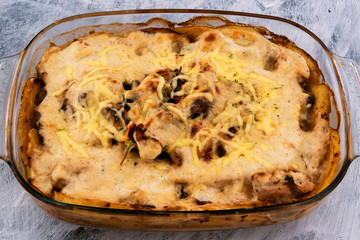 Cooked food in a glass container. Baked vegetables with mushrooms under cheese crust with mayonnaise. Delicious dinner for the whole family.