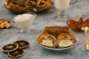 Cut pancake stuffed with cottage cheese. Delicious and nutritious breakfast. Dry lemon slices. Light background.