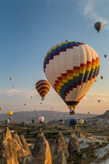 Hot air balloons flying at sunrise over rock formations in Cappadocia, Turkey