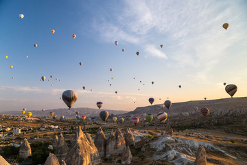 Hot air balloons flying at sunrise over rock formations in Cappadocia, Turkey