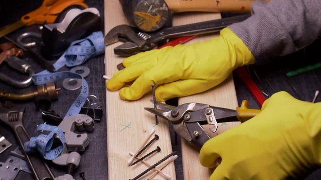 THE WRONG TOOL FOR THE JOB.  #3 IN A SERIES.  ECU SLIDER SHOT OF SOMEONE TRYING TO PULL OUT A NAIL WITH SHEET MAETAL CUTTERS.  IN 4K.