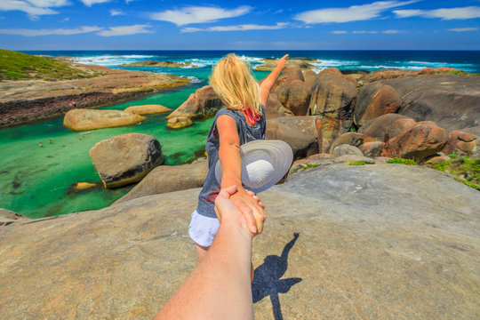 Follow me POV. Blonde woman holding hand of her friend at Elephant Rocks in Denmark, Western Australia. Girl enjoys of William Bay NP a popular Australian travel destination. Aerial view.