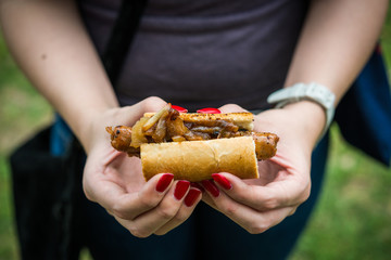 Close up photo of a sandwich with Spanish chistorra sausage and caramelized onion at a street food market