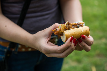 Close up photo of a sandwich with Spanish chistorra sausage and caramelized onion at a street food market