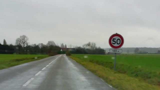 Interior vehicle point of view footage while driving in the rain in a rural area of France.