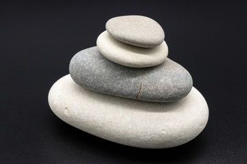Fototapeta na wymiar Stack of balanced zen pebbles on black background