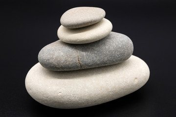 Fototapeta na wymiar Heap of balanced zen stones on black background